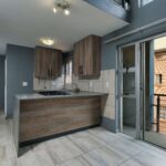 Spacious modern kitchen with wooden cabinets, balcony access, and ample natural light.