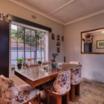 Inviting dining room featuring floral accents, wooden furniture, and a large window with garden view.